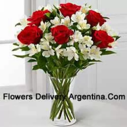 7 красных роз с разноцветными белыми цветами и наполнителями в стеклянной вазе